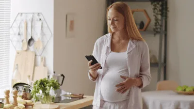 Pregnant woman checking her phone at home