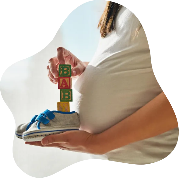 Expecting mother holding tiny baby shoes over her belly